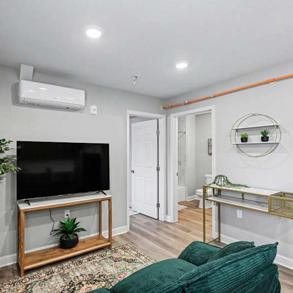 a living room with a television and a plant on a stand. at mayfair apartments, apartments, kansas city, mo