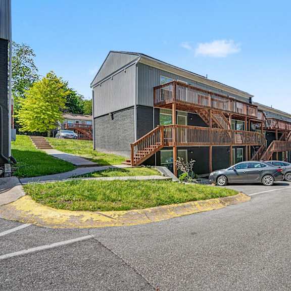 a parking lot with cars and a building with a wooden staircase.