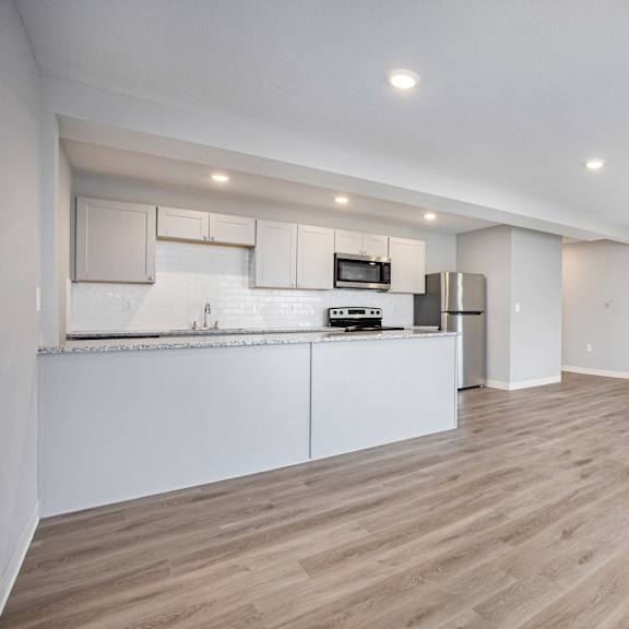 a kitchen with white cabinets and a wooden floor.at palisades apartments, kansas city, mo