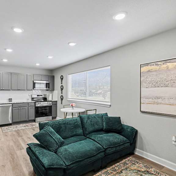 a living room with a green couch and a kitchen in the background  at mayfair apartments, kansas city