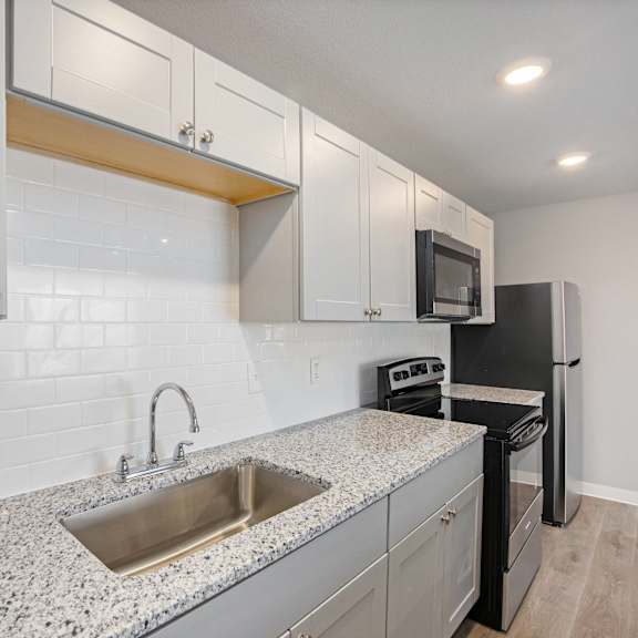 a kitchen with a sink, microwave, and oven.at palisades apartments, kansas city, mo