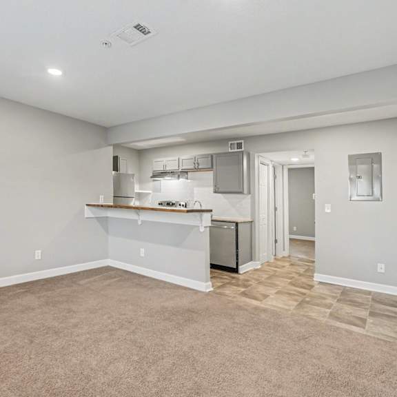 a spacious room with a kitchenette and a door leading to another room.
