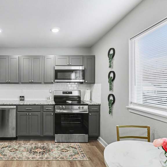 a modern kitchen with stainless steel appliances and grey cabinets at mayfair apartments, missouri