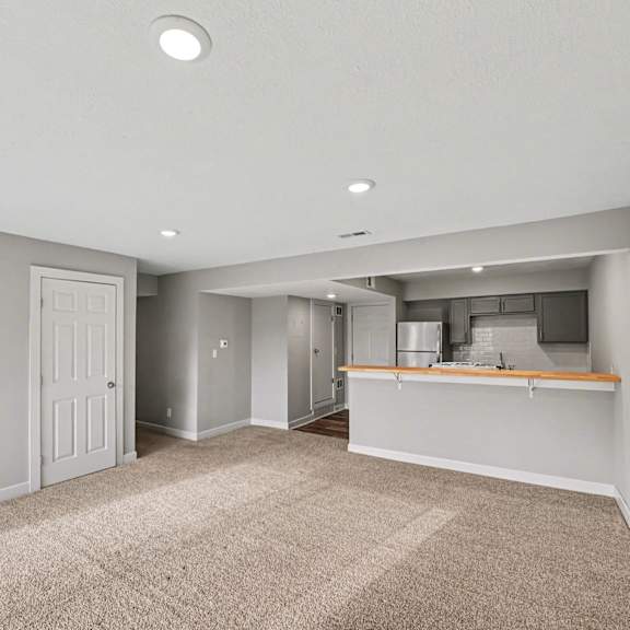a spacious room with a kitchenette and a door leading to another room.