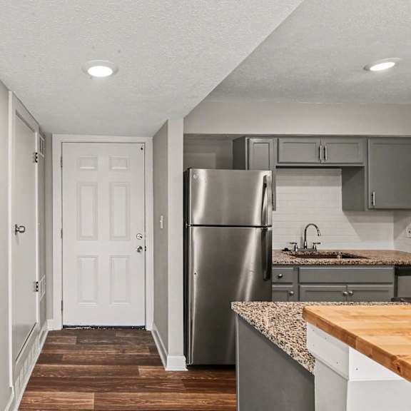 a kitchen with a refrigerator, sink, and cabinets.