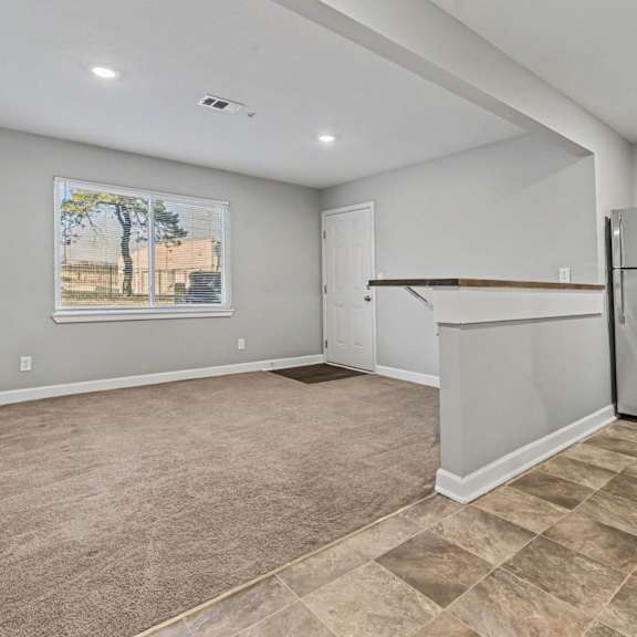 a spacious kitchen with a refrigerator and a painting of a tree on the wall.