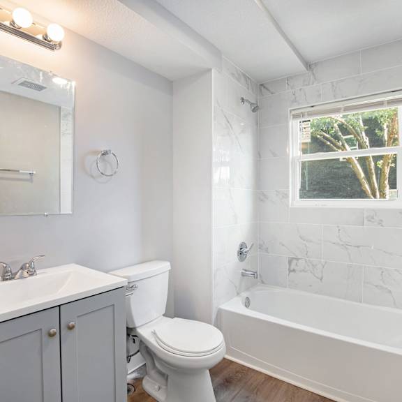 a white bathroom with a toilet, sink, and bathtub.at palisades apartments, kansas city, mo 64133