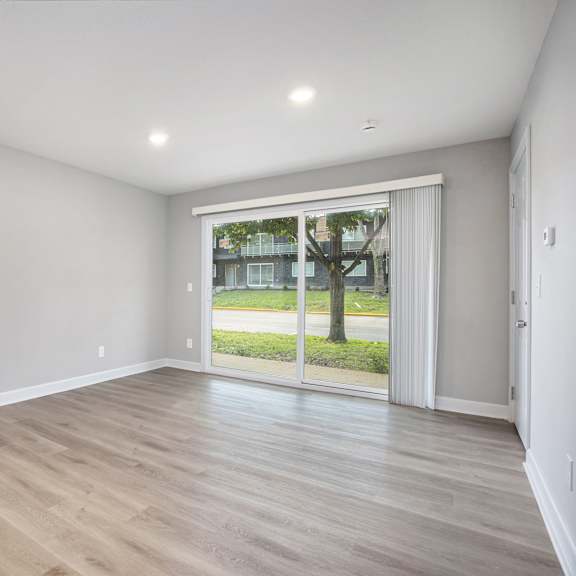 a room with wooden flooring and a sliding glass door leading to a balcony.at palisades apartments, kansas city, mo 64133