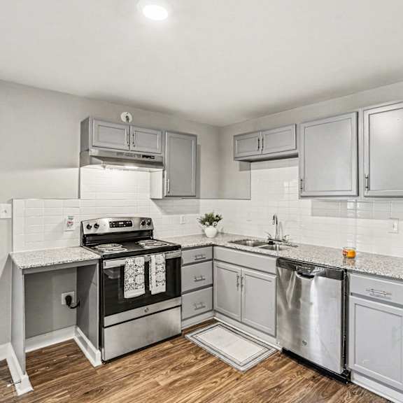 a modern kitchen with stainless steel appliances and a wooden floor.