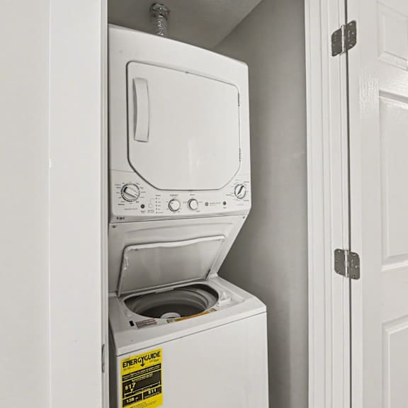 a white dryer is in a small closet.