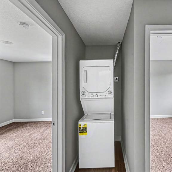 a white fridge in a room with a carpet floor.