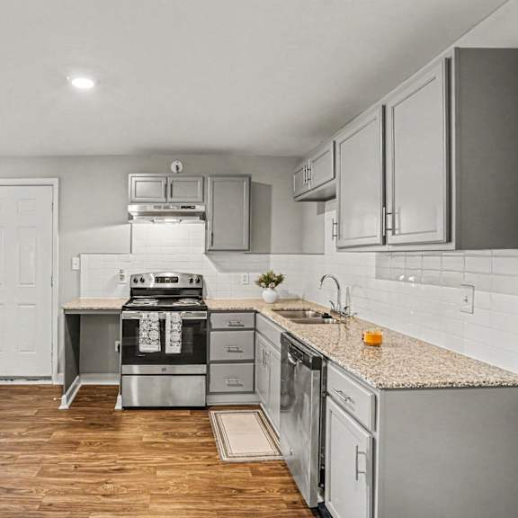 a modern kitchen with stainless steel appliances and wooden flooring.