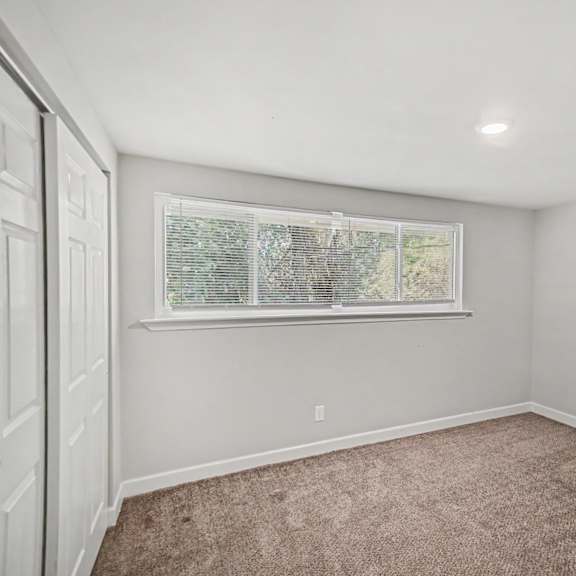 a room with a carpeted floor and a window with blinds.