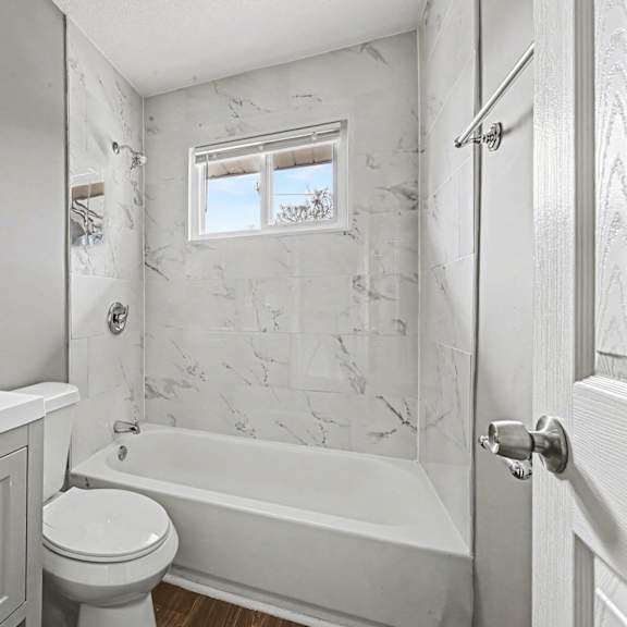 a white bathroom with a marble patterned wall.