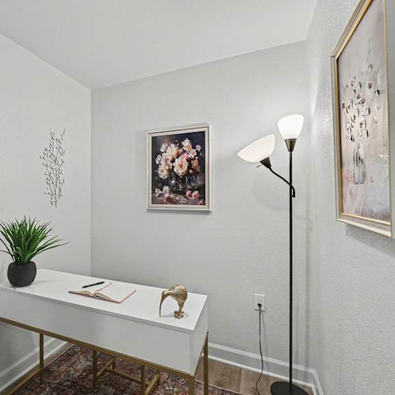 a white desk with a plant on it and a picture of flowers on the wall at mayfair apartments, kansas city, missouri