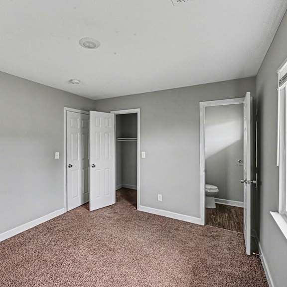 a room with a carpeted floor and a window on the right side.