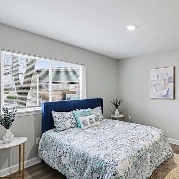 a bedroom with a bed, a plant, and a painting on the wall at mayfair apartments, kansas city