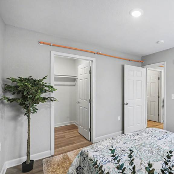 a bedroom with a bed, a plant, and a painting on the wall at mayfair apartments, missouri