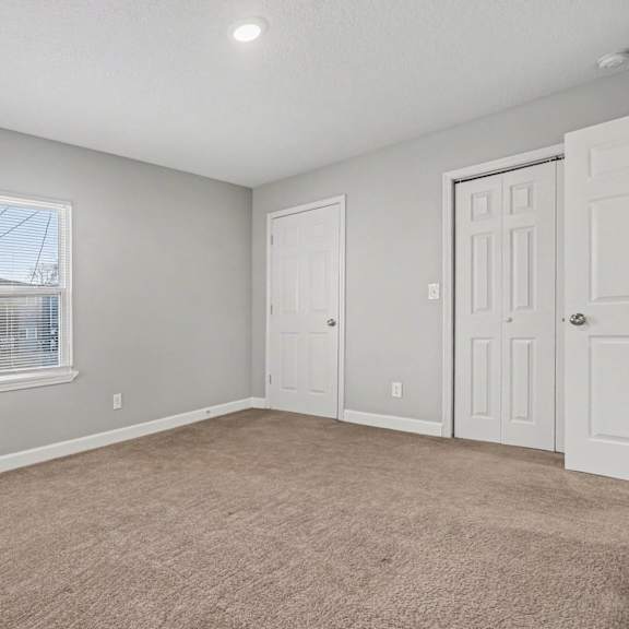 a room with a carpeted floor and two doors.