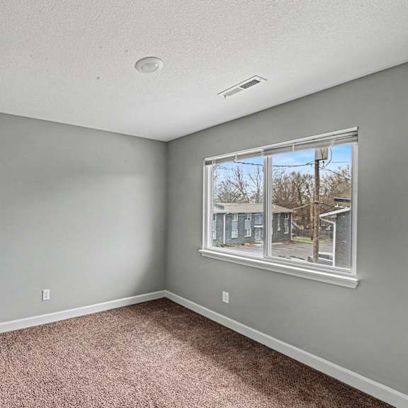 a room with a carpeted floor and a window showing a building outside.