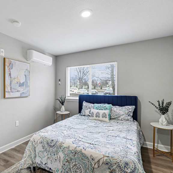 a bedroom with a bed, a painting, a window, and a plant at mayfair apartments, missouri, 64145