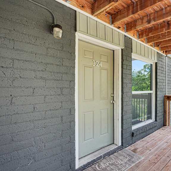 a wooden deck with a white door and a brick wall.