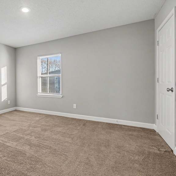a room with a carpeted floor and a window with blinds.