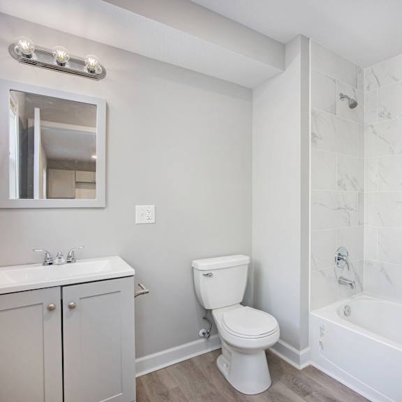 a white bathroom with a marble tile shower.at palisades apartments, kansas city