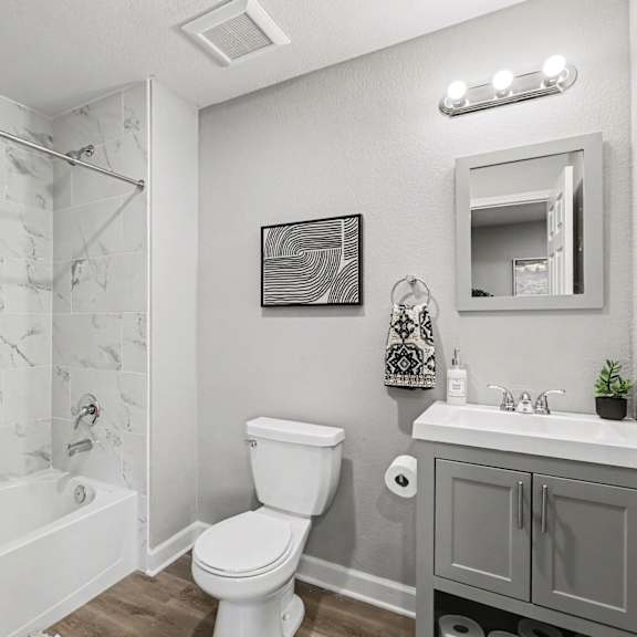 a bathroom with a white toilet, a white sink, and a shower with a curtain. at mayfair apartments, apartments, kansas city, mo