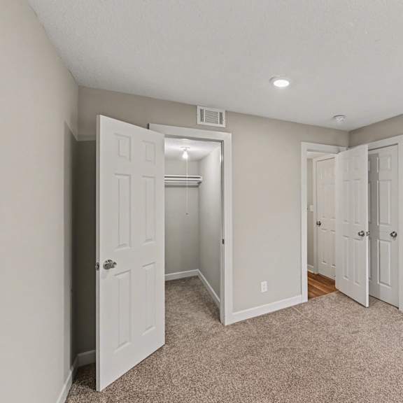 a room with a carpeted floor and two white doors.