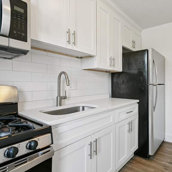 a black refrigerator is in a kitchen with white cabinets at shipyard shores apartments, newport news, va, 23607