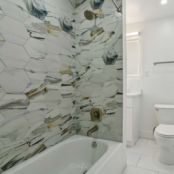 a white toilet sits in a bathroom with a glass mosaic wall at shipyard shores apartments, newport news