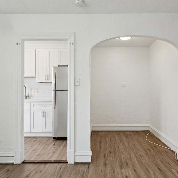 a kitchen with white cabinets and a refrigerator is visible through an open doorway at shipyard shores apartments, apartments, newport news, va