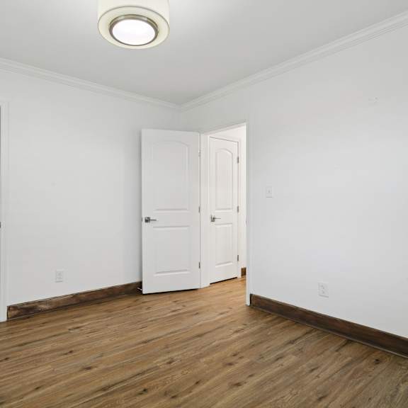 a room with two white doors and a wooden floor at shipyard shores apartments, virginia