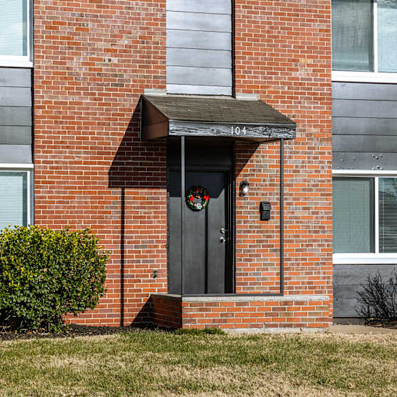 a red brick building with a black door and a small porch. at blacklark apartments, apartments, kansas city, ks