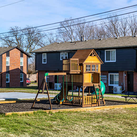 a playground with a basketball hoop and a wooden swing set. at blacklark apartments, kansas city, ks, 66101