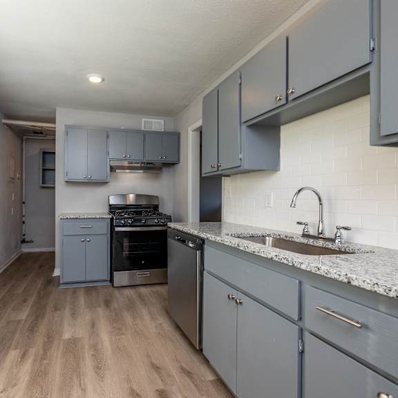 a kitchen with a sink, stove, and cabinets. at blacklark apartments, kansas