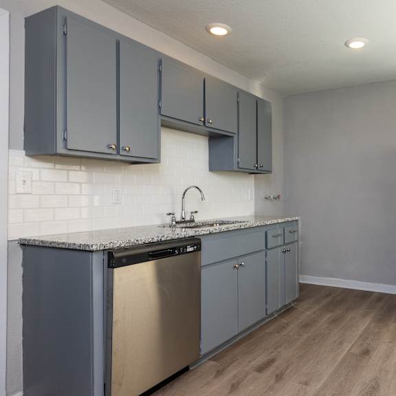 a kitchen with a black refrigerator and a stainless steel dishwasher. at blacklark apartments, apartments, kansas city, ks