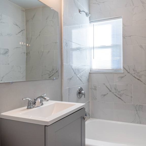 a bathroom with a marble wall and a white sink. at blacklark apartments, kansas, 66101