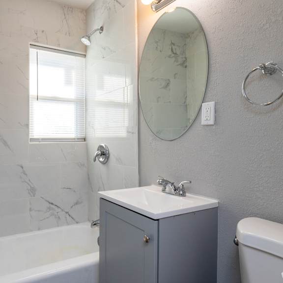 a bathroom with a marble wall and a round mirror. at blacklark apartments, kansas city, ks, 66101