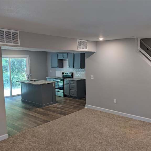 a living room with a kitchen and stairs