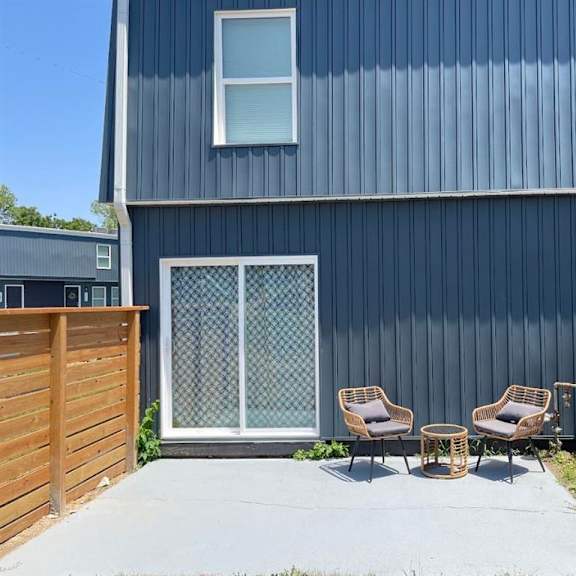 a patio with two chairs in front of a blue building