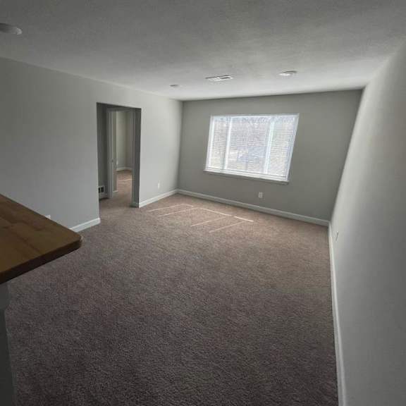 a living room with a wooden mantle and a window