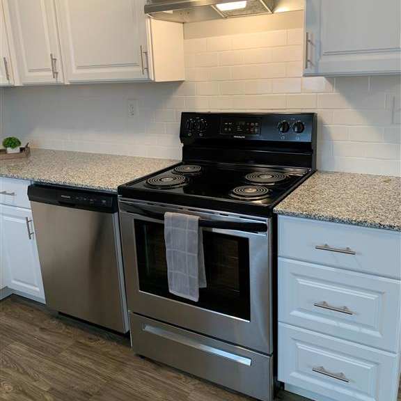 a kitchen with a stove and a microwave and white cabinets