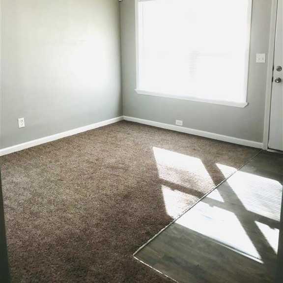 an empty living room with a large window and carpet