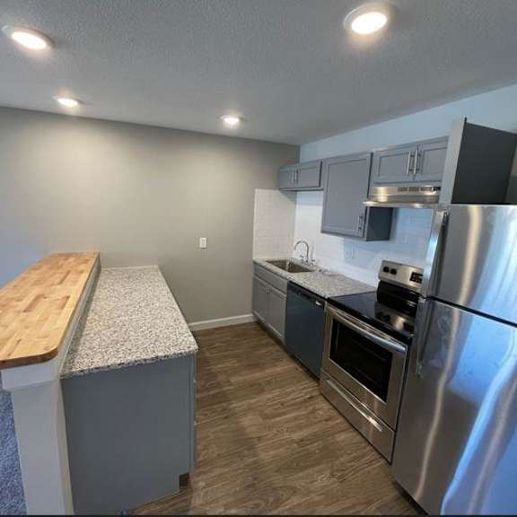 a kitchen with stainless steel appliances and a wooden counter top