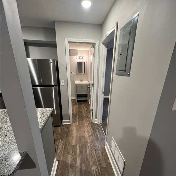 a hallway with a kitchen and a refrigerator