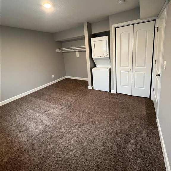 a bedroom with a closet and a stackable washer and dryer