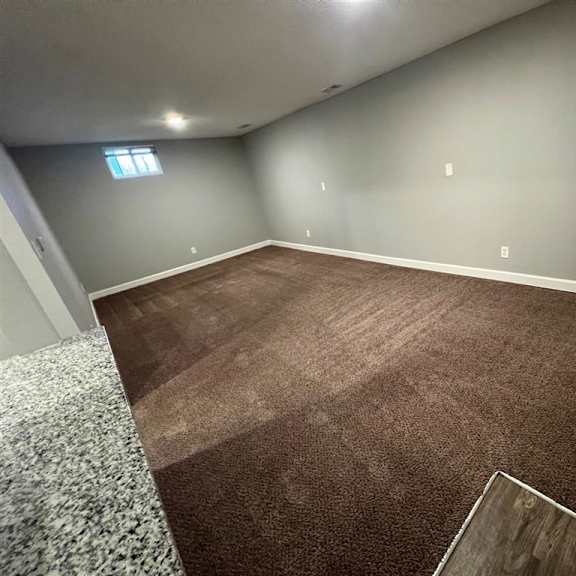 a empty living room with carpet and a window
