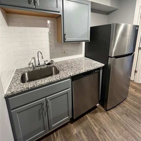 a kitchen with a sink and a stainless steel refrigerator